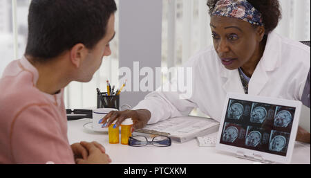 Middle aged black doctor talking with patient sur ct-scans et des médicaments Banque D'Images