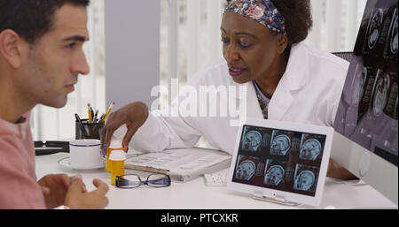 Middle aged black doctor talking with patient sur ct-scans et des médicaments Banque D'Images