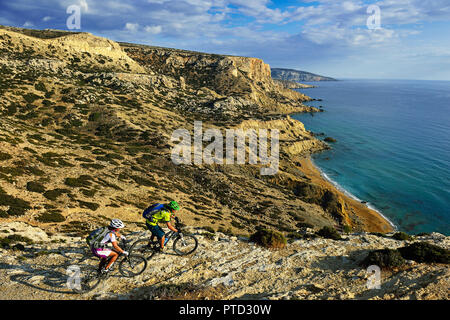 Deux cyclistes de montagne randonnée le long de la côte rocheuse, plage rouge, Matala, Crète, Grèce Banque D'Images