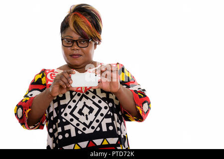 Studio shot of fat black African woman taking picture avec mobil Banque D'Images