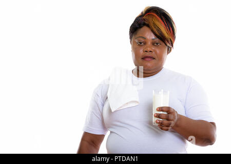 Studio shot of fat black African woman holding glass of milk rea Banque D'Images