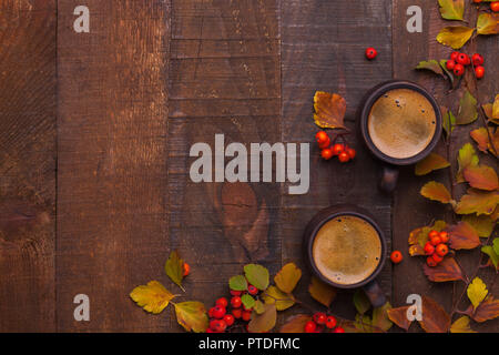 Argile brun deux tasses de café noir et de branches de feuilles d'automne (Spiraea vanhouttei) avec de petits fruits rouges Rowan sur la vieille table en bois. Vue d'en haut Banque D'Images