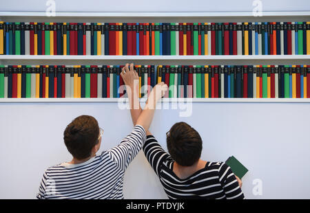 Francfort, Allemagne. 09 octobre 2018, Hessen, Frankfurt Main  : Martha Schoknecht (l) et Ruth Schildknecht mettre des livres sur une étagère dans le stand de Diogenes Verlag Zurich au Salon du livre de Francfort. Le plus grand book show aura lieu du 10 au 14 octobre. Photo : Arne Dedert/dpa Banque D'Images