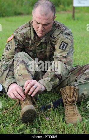 La CPS de l'armée américaine. Luke Carter, 52e Groupe de munitions (NEM), enlève ses bottes après un ruck mars, Aberdeen Proving Ground, Md., 11 juillet 2017. Le 20e Concours de meilleur guerrier CBRNE est un concours au niveau de la division qui permettra d'identifier un soldat et un sous-officier à passer à la concurrence FORSCOM Meilleur guerrier. Banque D'Images