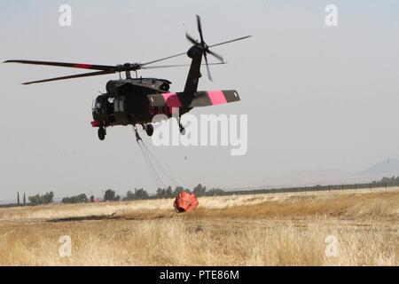 La Garde Nationale de Californie UN UH-60 Black Hawk quitte l'Aéroport Municipal de Coalinga le 13 juillet à la bataille de Garza incendie dans le comté de Kings, en Californie. Cinq Black Hawks de CalGuard ont répondu à l'incendie, l'un de Garza près de deux douzaines de feux de flambage le Golden State à la mi-juillet 2017. Il avait déjà consommé plus de 26 000 acres et a été de 30 pour cent par la Californie, ministère des Forêts et de protection contre l'incendie (CAL). Banque D'Images