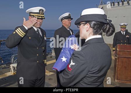 Mer Méditerranée (16 juillet 2017) Le Cmdr. Troy Denison, commandant de l'USS destroyer lance-missiles Truxtun (DDG 103) rend un hommage en tant que spécialiste des programmes religieux 2e classe Maria Perez se prépare à passer l'enseigne pendant un enterrement en mer la cérémonie. Truxtun, partie de la George H. W. Groupe aéronaval du Bush (GHWBCSG), mène des opérations navales dans la sixième flotte américaine zone d'opérations à l'appui de la sécurité nationale des États-Unis en Europe et en Afrique. Banque D'Images