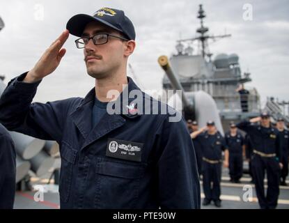 Inde (14 juillet 2017) Technicien Sonar (surface) 2e classe Nash Blun, de Flowery Branch, Ga., salue l'enseigne au cours de matin à bord de la couleurs de la classe Ticonderoga croiseur lance-missiles USS Princeton (CG 59). Princeton est actuellement à la phase en mer de Malabar en 2017. 2017 Malabar est la dernière d'une série d'exercices entre la marine indienne, l'auto-défense maritime du Japon et de la Marine qui a pris de l'ampleur et de la complexité au fil des ans pour répondre à la variété des menaces communes à la sécurité maritime dans l'Indo-Asia pacifique. Banque D'Images