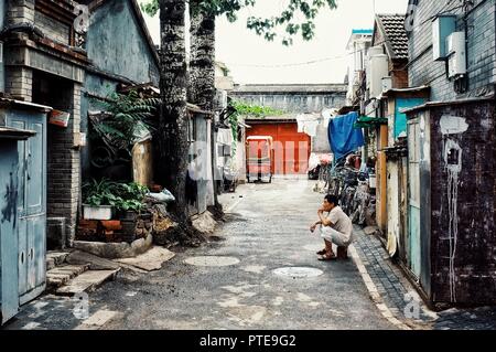 Beijing / Chine - 24 juin 2011 : l'homme attendant à l'extérieur de sa maison dans une ville typique hutong Banque D'Images