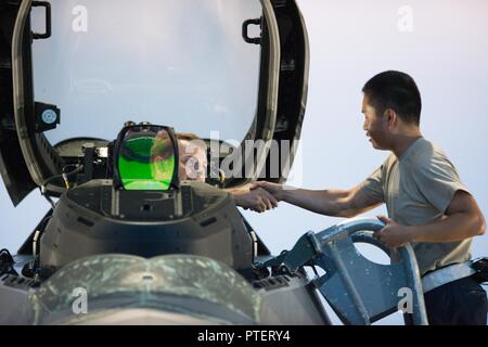 U.S. Air Force d'un membre de la 1re classe Andy Luong, 1e Escadron de maintenance crew chief, serre la main avec un 94e Escadron de chasse pilote avant son départ du Joint Base Langley-Eustis, en Virginie, le 11 juillet 2017. Les pilotes affectés à la 1e Escadre de chasse, participer à des opérations de vol de nuit pour maintenir le niveau de connaissances sur l'utilisation de la vision nocturne tout en volant. Banque D'Images