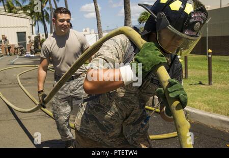 Axton Ching, Civil Air Patrol cadet, porte une lance à incendie avec de hauts Airman Louie Saiz, 647e Escadron de génie civil pompier, lors d'une patrouille de l'aviation civile, visite à la 15e Escadre dans le cadre de leur campement, Joint Base Harbor-Hickam Pearl, Washington, le 14 juillet 2017. Le stationnement est un programme d'une semaine, pendant laquelle les cadets sont immergés dans une modification de l'environnement de formation de base de l'Armée de l'air. Les cadets ont enseigné les rudiments de la vie militaire avec, physiquement et mentalement. Banque D'Images