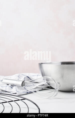 Concept de cuisson. Bol avec un fouet, et torchon grille française sur table en marbre blanc sur fond rose avec copie espace. Banque D'Images