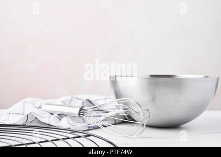 Concept de cuisson. Bol avec un fouet, et torchon grille française sur table en marbre blanc sur fond rose avec copie espace. Banque D'Images