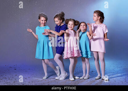 Des enfants heureux groupe dans des vêtements pour dame les filles. Concept de la mode, maison de vacances, Noël, nouvel an, x-mas, l'hiver. Cinq enfants dans de belles robes profiter de la neige à la veille de la nouvelle année. Studio shot. Banque D'Images