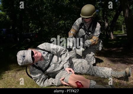 U.S. Air Force Tech. Le Sgt. Katherine Robbins, assiste à à la simulation de blessures du lieutenant-colonel Tammy King, tous deux de la 119e Groupe médical, au cours d'un scénario de formation au Camp Gilbert C. Grafton, Dakota du Nord, le 19 juillet 2017. Ils participent à des opérations militaires en territoire urbain (MOUT) formation combinée à la formation y compris les pertes au combat victimes simulées utilisant moulage. Banque D'Images