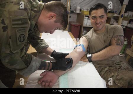 La CPS de l'armée américaine. Ryan Cote, déployées à l'appui de la Force opérationnelle interarmées - Fonctionnement résoudre inhérent et affecté à la 2e Brigade Combat Team, 82e Division aéroportée, pratiques donnant un IV au 1er lieutenant Jose Funes sur Qayyarah Aérodrome de l'Ouest, de l'Iraq, le 21 juillet 2017. La 2ème BCT, 82ème Abn. Div., permet aux partenaires des forces de sécurité iraquiennes dans le but d'aider et de conseiller, planification de la mission de contribuer, collecte et analyse des renseignements, la protection de la force et la précision de forêt pour atteindre la défaite militaire d'ISIS. Les GFIM-OIR est la Coalition mondiale pour vaincre ISIS en Iraq et en Syrie. Banque D'Images