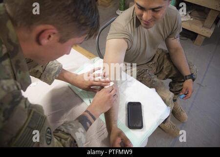 La CPS de l'armée américaine. Ryan Cote, déployées à l'appui de la Force opérationnelle interarmées - Fonctionnement résoudre inhérent et affecté à la 2e Brigade Combat Team, 82e Division aéroportée, pratiques donnant un IV au 1er lieutenant Jose Funes sur Qayyarah Aérodrome de l'Ouest, de l'Iraq, le 21 juillet 2017. La 2ème BCT, 82ème Abn. Div., permet aux partenaires des forces de sécurité iraquiennes dans le but d'aider et de conseiller, planification de la mission de contribuer, collecte et analyse des renseignements, la protection de la force et la précision de forêt pour atteindre la défaite militaire d'ISIS. Les GFIM-OIR est la Coalition mondiale pour vaincre ISIS en Iraq et en Syrie. Banque D'Images