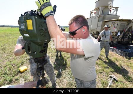 Oregon Air National Guard, 270e Escadron de contrôle de la circulation aérienne, l'airman Joshua Clements utilise le Pinunjar gas powered jack hammer pour établir une connexion à la masse appropriée pour le contrôle aérien tactique et l'unité de navigation (arrière-plan) à l'agression de l'air d'une bande au Fort McCoy, Wisconsin (Etats-Unis), le 19 juillet 2017. Le contrôle aérien tactique et un équipement de navigation (TACN) est un appareil de navigation radio sida pilotes pendant le décollage et l'atterrissage. Banque D'Images