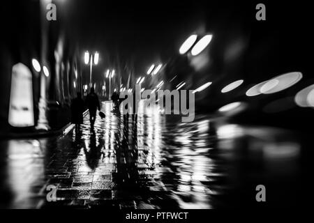 Silhouettes de gens comme zombie marcher la nuit dans la saison des pluies à la lumière des lampes de la rue,soft focus brouillée. Banque D'Images