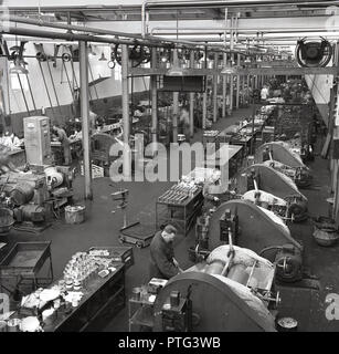 Années 1950, historique, vue aérienne de l'intérieur d'une usine de fabrication des peintures montrant les travailleurs de sexe masculin à l'aide de machines industrielles, et des pots de peinture mixte assis sur chariots métalliques, England, UK. Banque D'Images