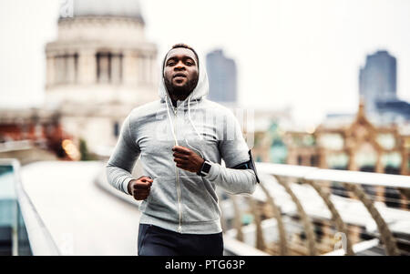 Young black man runner s'exécutant sur le pont à l'extérieur dans une ville. Banque D'Images