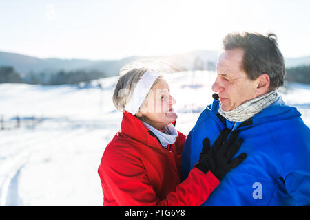 Senior couple porteur debout dans la nature, le repos d'hiver. Banque D'Images