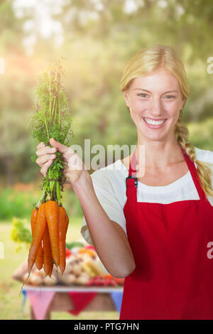 Image composite de portrait of smiling young woman holding carrots Banque D'Images