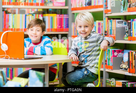 Frères dans la bibliothèque des livres de lecture et l'écoute audio s'amusant Banque D'Images