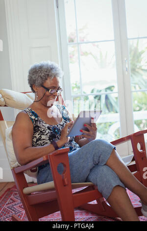 Senior woman using digital tablet in rocking chair Banque D'Images