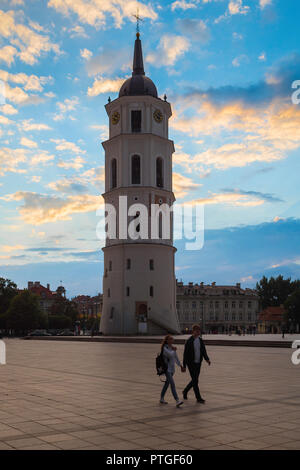 Bell Tower, Vilnius voir au crépuscule d'un jeune couple en train de marcher à travers la place de la Cathédrale avec les 57m de haut beffroi derrière eux, Vilnius, Lituanie. Banque D'Images