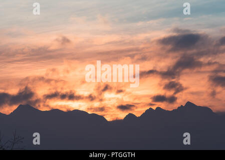 Coucher du soleil orange avec des pics de montagne, avec des nuages, bleu, jaune orange, moelleux. Banque D'Images