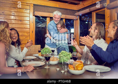 Les Amis des mains pour tendre couple hugging at dinner table Banque D'Images