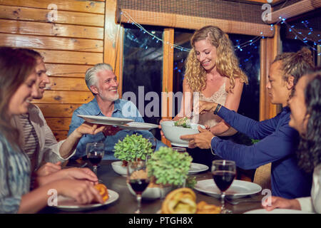 Femme servant le dîner d'amis à la table de salle à manger cabine Banque D'Images