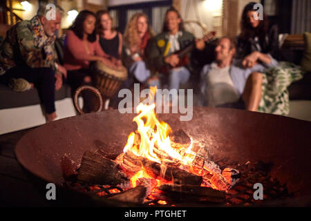 Amis, jouer de la musique sur le patio à côté de feu de camp Banque D'Images