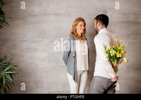 Voir à man giving bouquet de tulipes jaunes à sa petite amie Banque D'Images