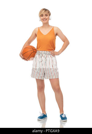 Smiling teenage girl in headphones avec basket-ball Banque D'Images