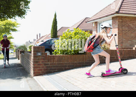 Girl riding scooter à sunny driveway Banque D'Images