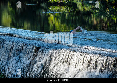 Jens nageur Roesner prend un pre-work wild nager dans la rivière Avon à Warleigh Weir dans le Somerset. Banque D'Images