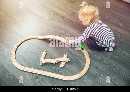 Little girl Playing with wooden railway sur marbre à la maison Banque D'Images