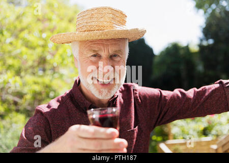 Portrait confiant senior man drinking red wine in garden Banque D'Images