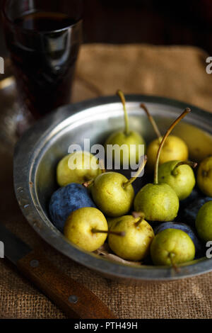 Poirier et les prunes dans un bol en métal et un verre de vin maison style rustique Banque D'Images