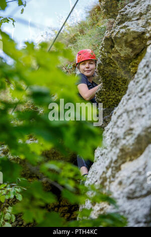 Photo de fille en rouge grimpeur helmet on mountain Banque D'Images