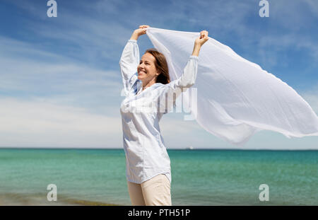 Femme heureuse avec châle dans le vent sur la plage Banque D'Images