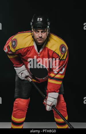 Joueur professionnel de hockey sur glace holding bâton de hockey et looking at camera sur noir Banque D'Images