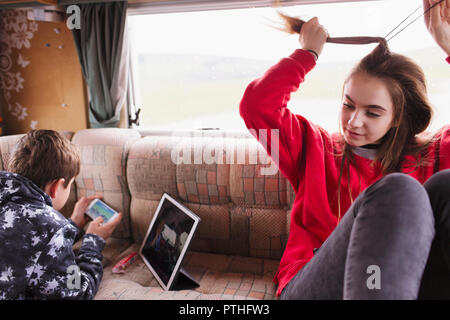 Les frère et soeur, relaxant using digital tablet et smart phone dans motor home Banque D'Images