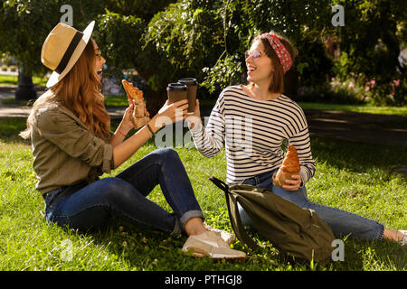 Deux jeunes filles happy friends having fun at the park, un pique-nique avec croissants et café Banque D'Images