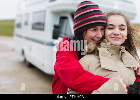 Tendre mère et fille dans des vêtements chauds hugging hors motor home Banque D'Images