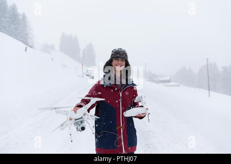 Portrait of smiling teenage boy with drone dans paysage de neige Banque D'Images