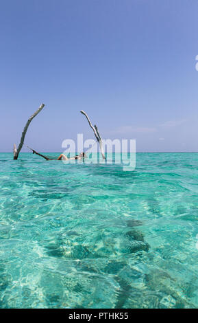 Young woman in hammock sur l'océan bleu tranquille, Maldives, océan Indien Banque D'Images