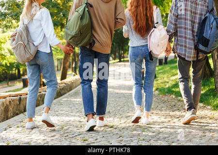 Vue arrière de l'image recadrée groupe d'étudiants avec des sacs à dos marche à l'extérieur du campus Banque D'Images