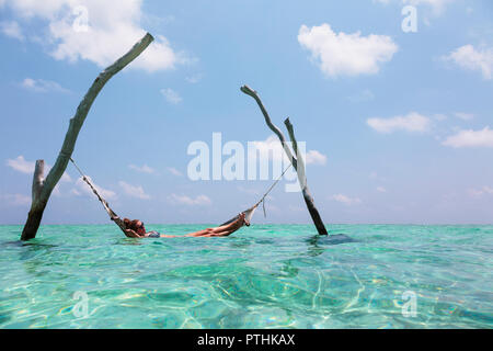 Woman laying in hammock sur océan tranquille, Maldives, océan Indien Banque D'Images